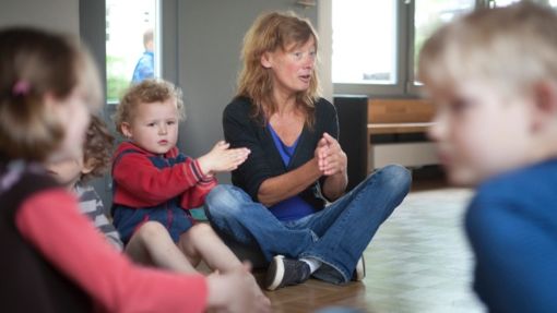 Kleinkinder in einer Spielgruppe mit Leiterin, die Spiele macht