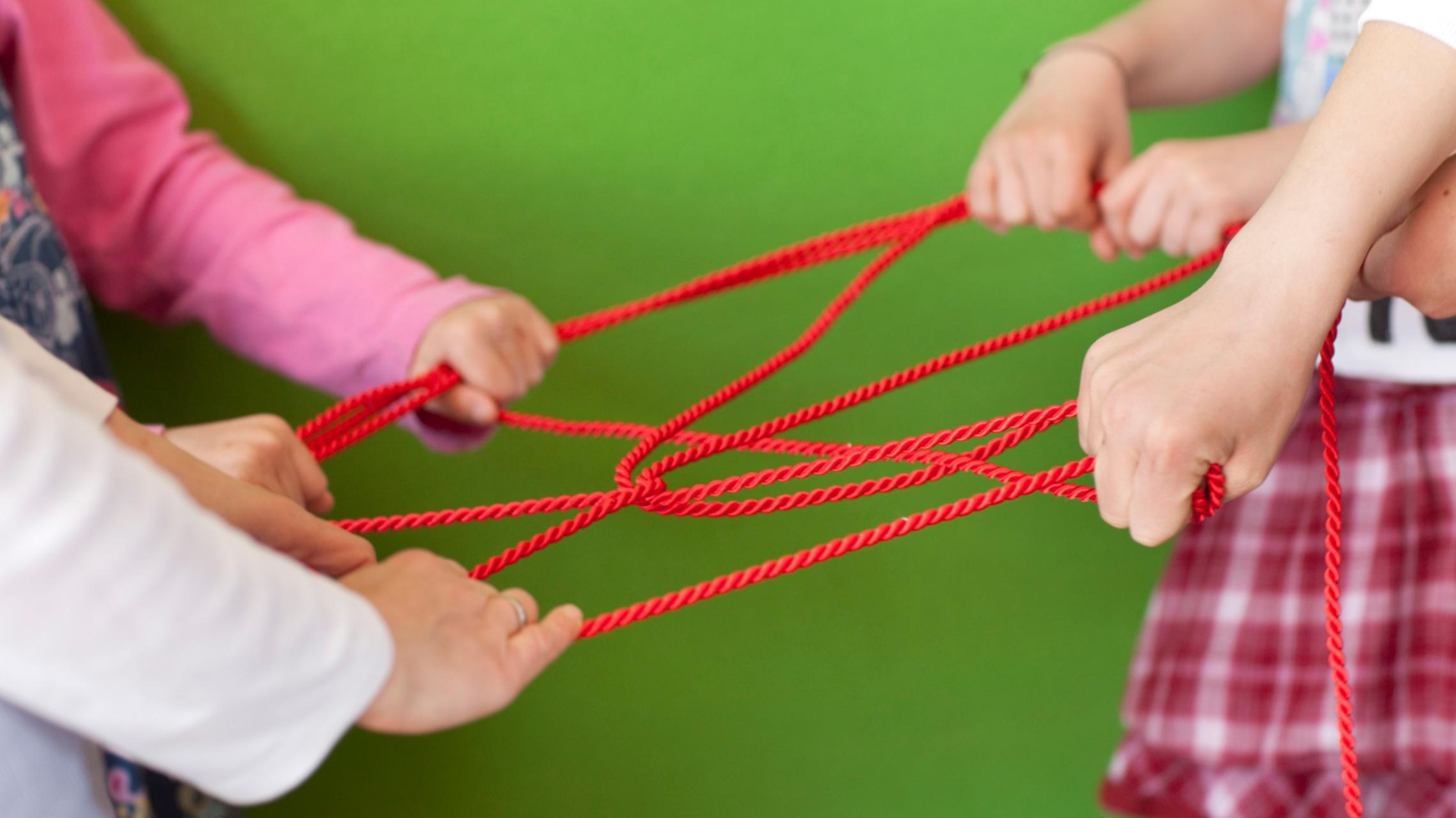 2 Hände, die ein Netzwerk mit Seilen bilden