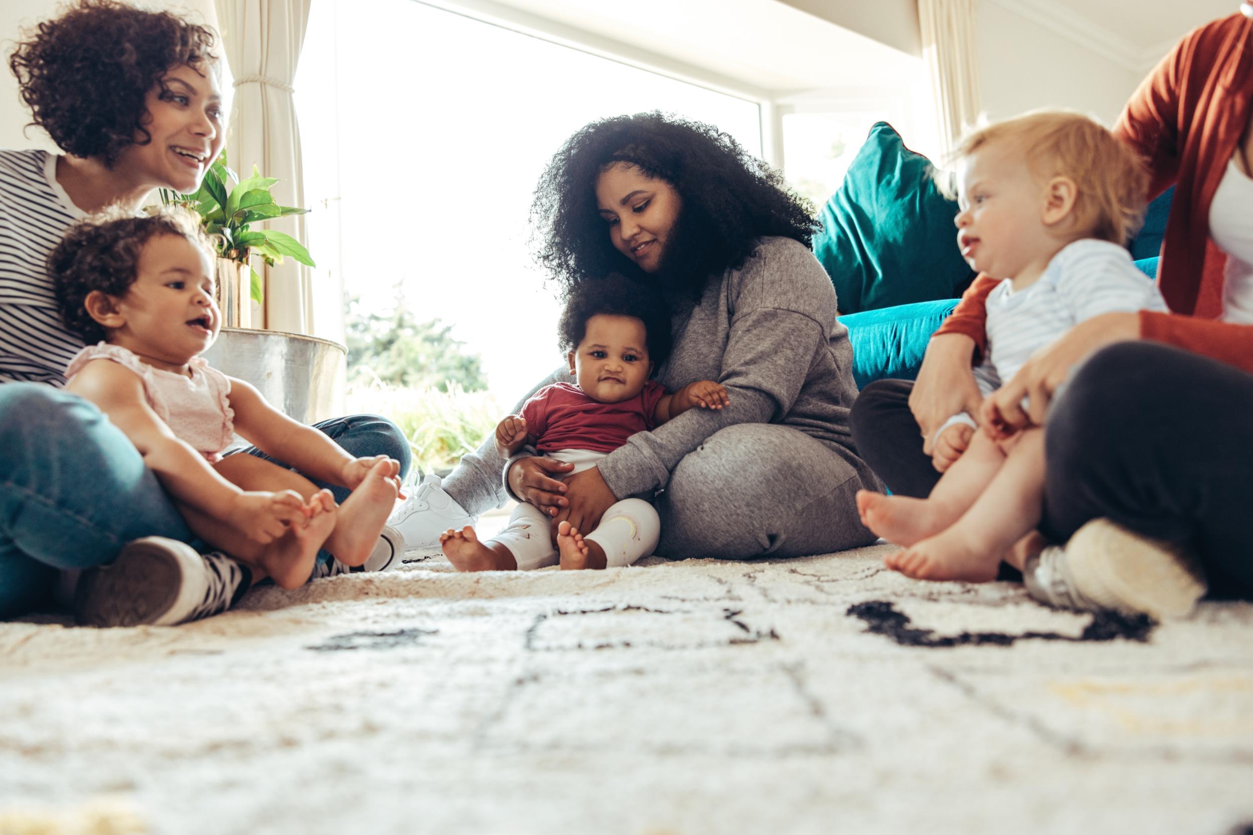 Mehrere Frauen sitzen zusammen mit ihren Kindern auf dem Boden