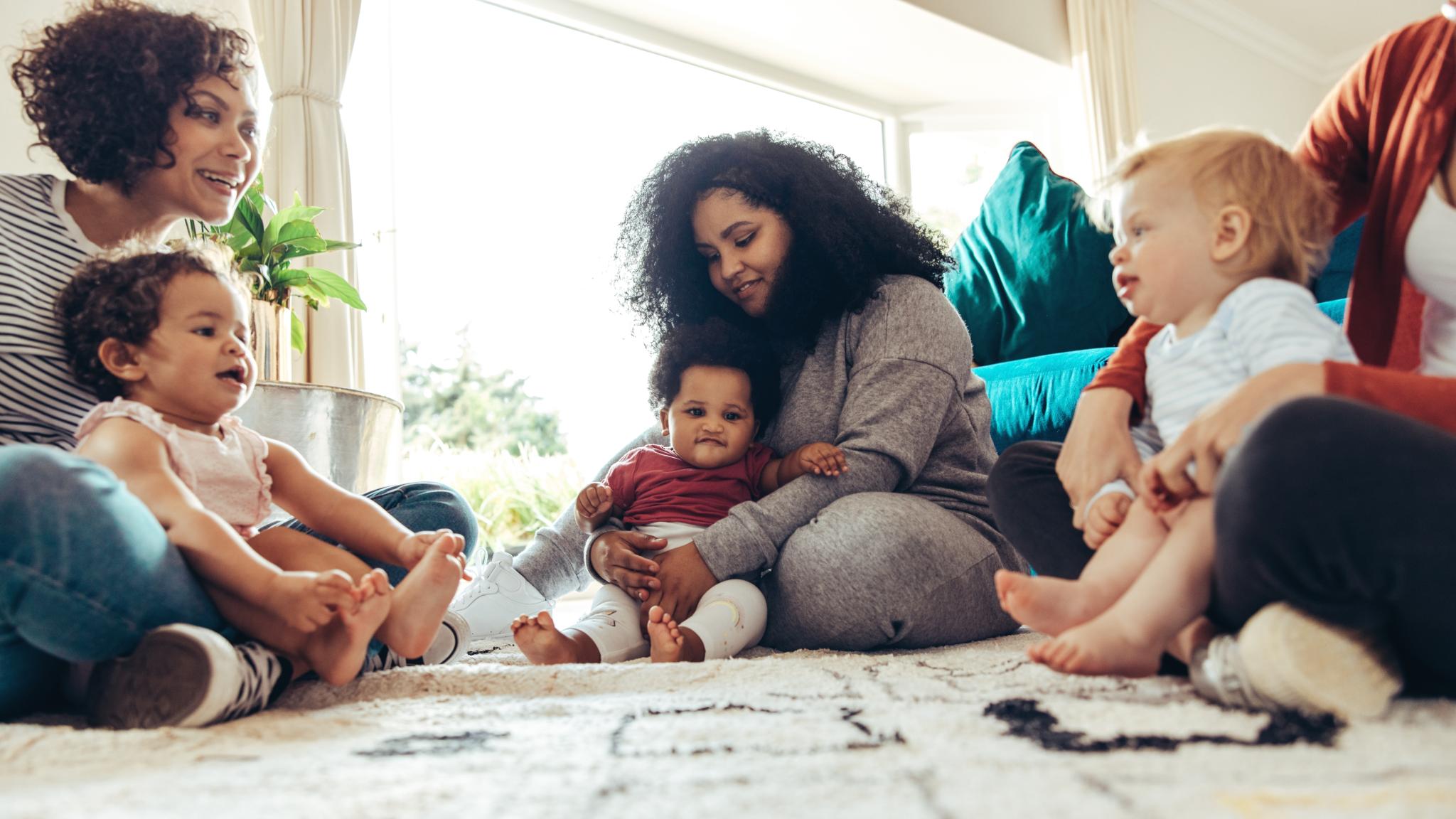 Mehrere Frauen sitzen zusammen mit ihren Kindern auf dem Boden