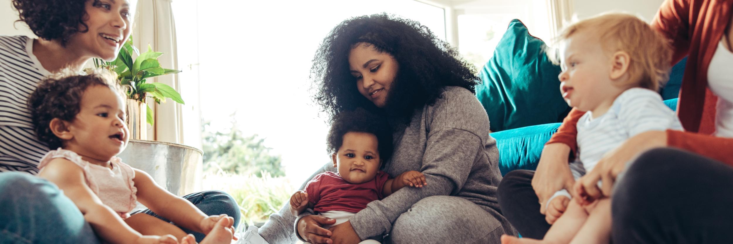 Mehrere Frauen sitzen zusammen mit ihren Kindern auf dem Boden
