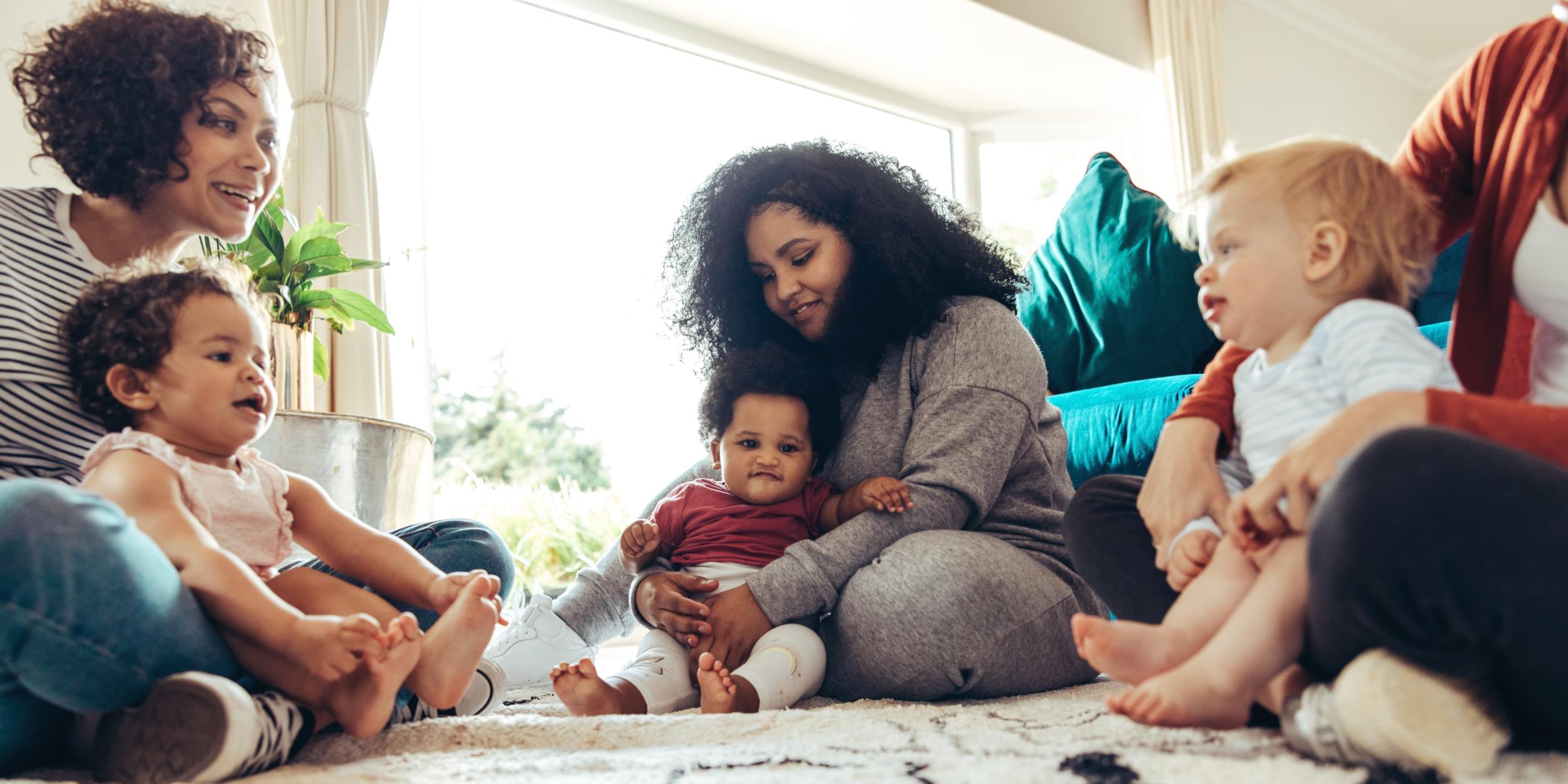 Mehrere Frauen sitzen zusammen mit ihren Kindern auf dem Boden