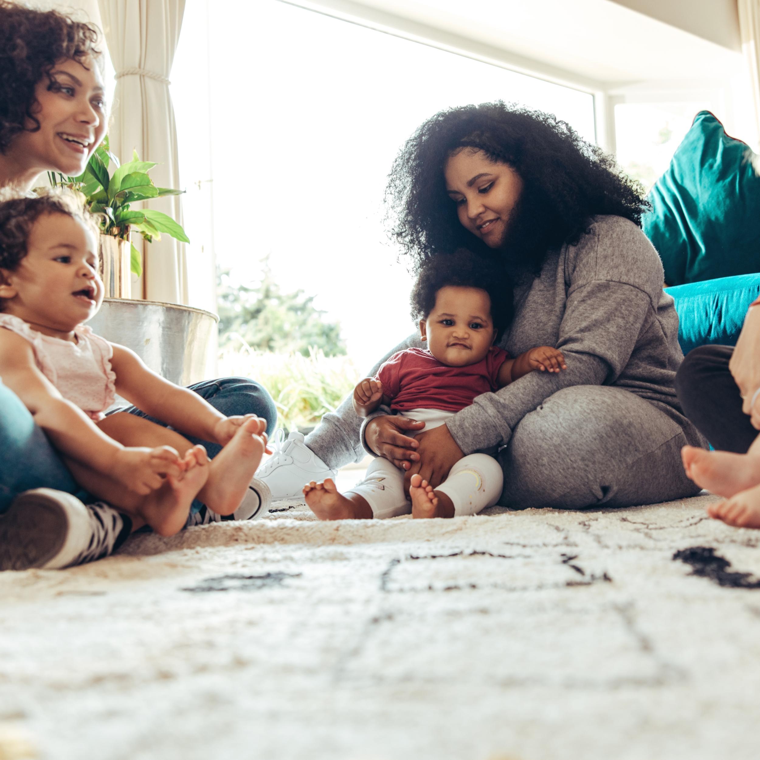 Mehrere Frauen sitzen zusammen mit ihren Kindern auf dem Boden