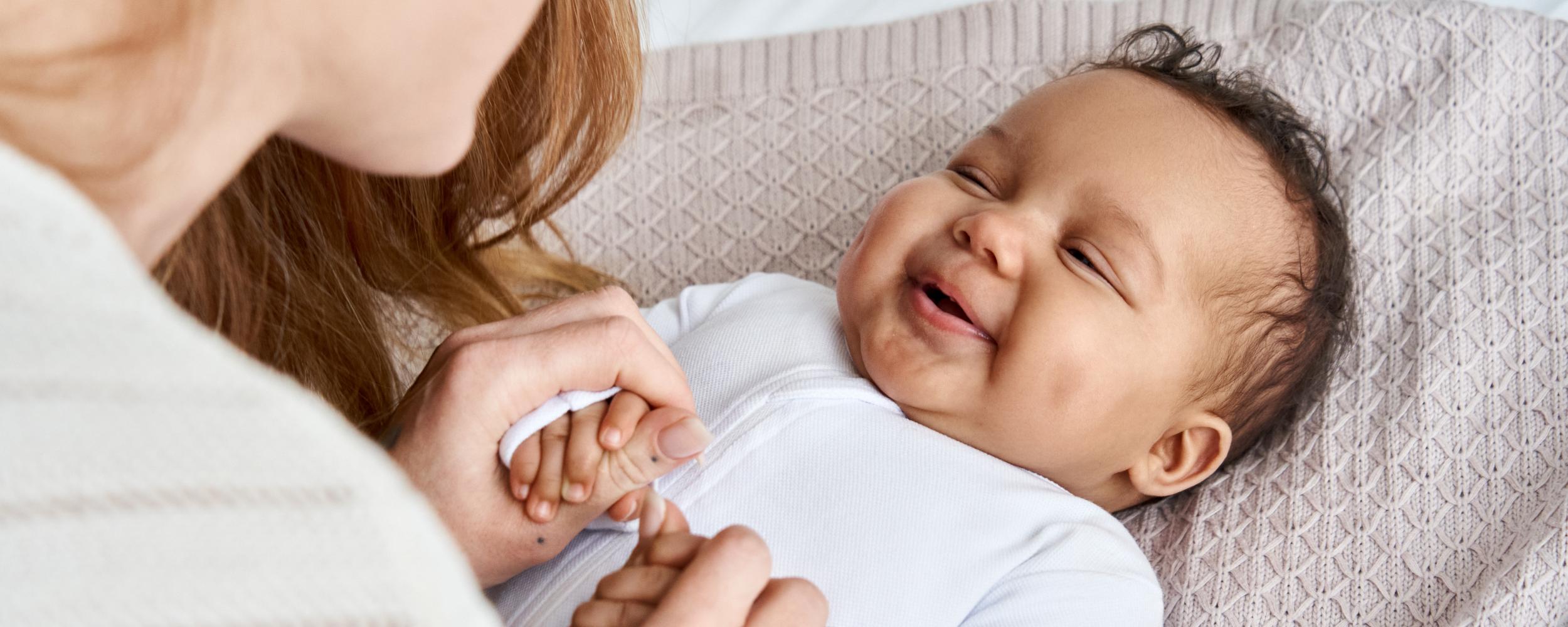 Eine Mutter schaut ihr Baby an, das Baby lacht.