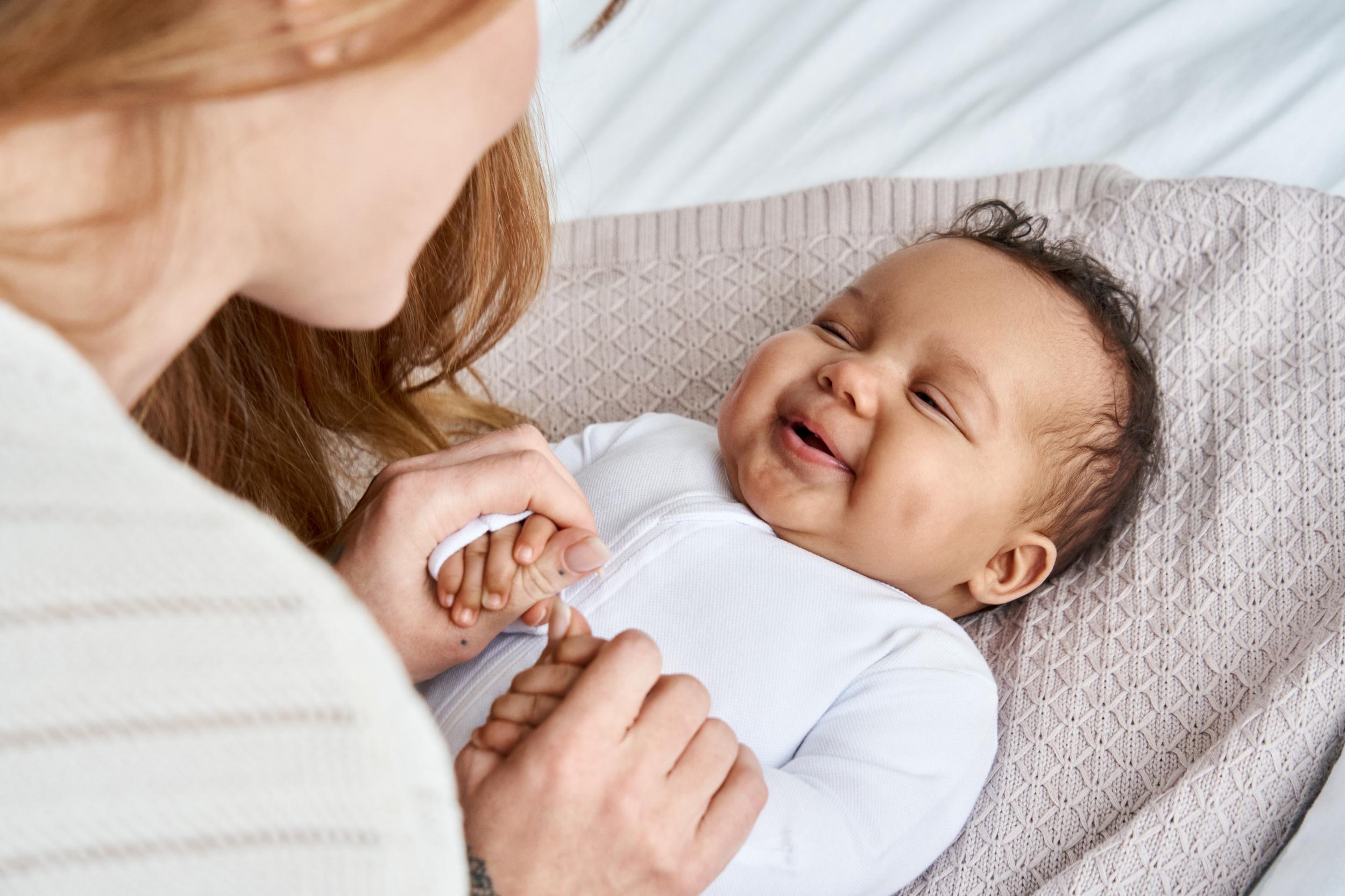 Eine Mutter schaut ihr Baby an, das Baby lacht.