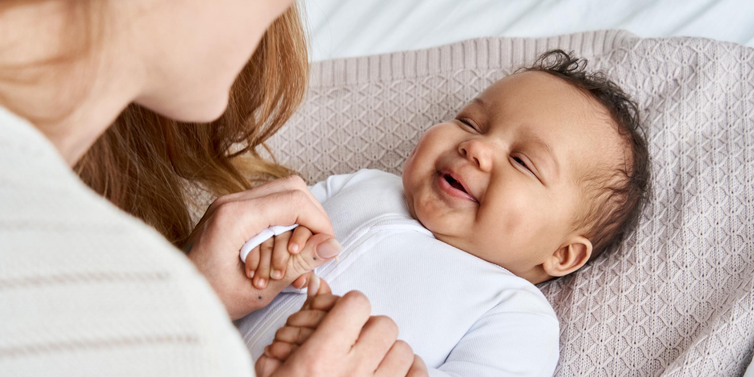 Eine Mutter schaut ihr Baby an, das Baby lacht.