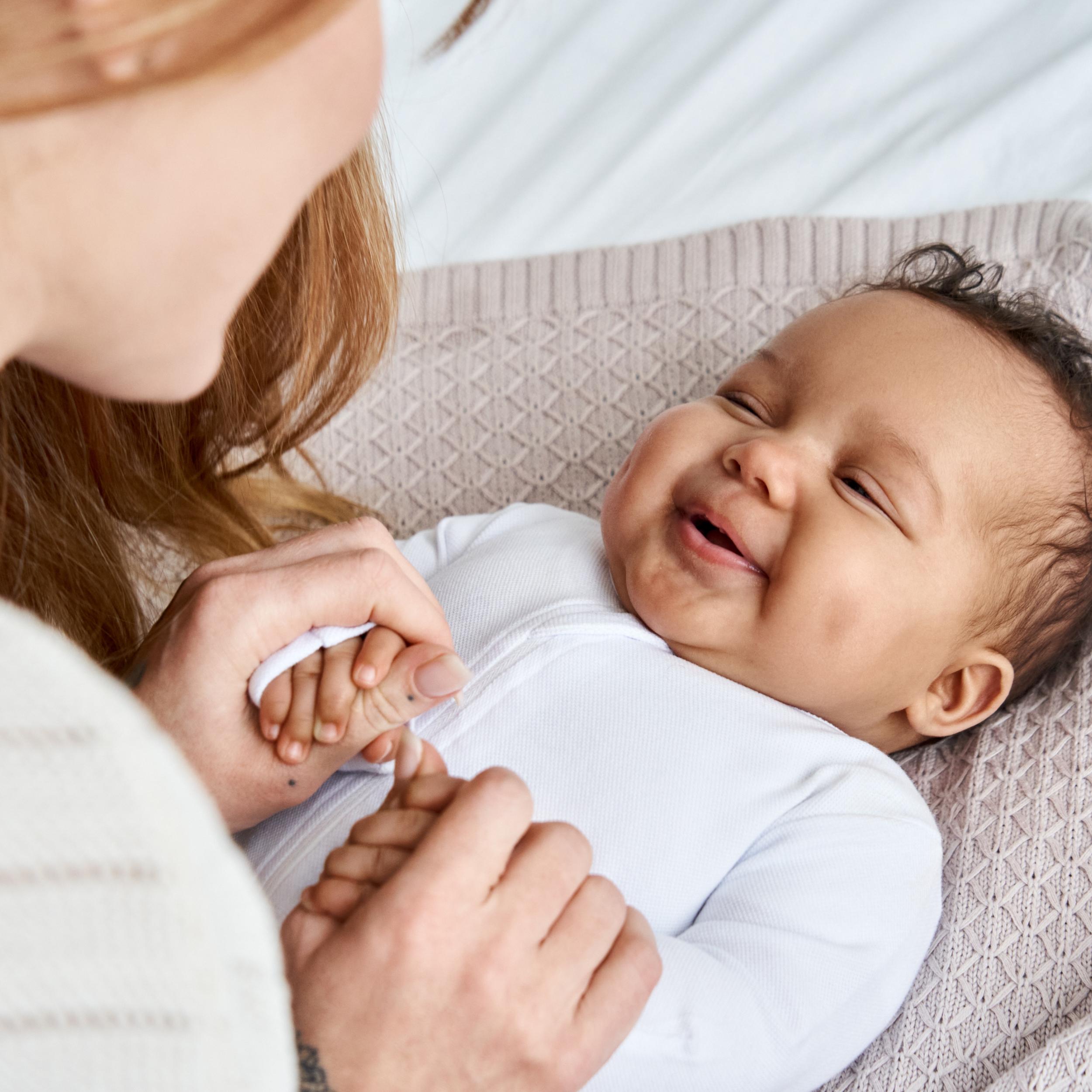 Eine Mutter schaut ihr Baby an, das Baby lacht.