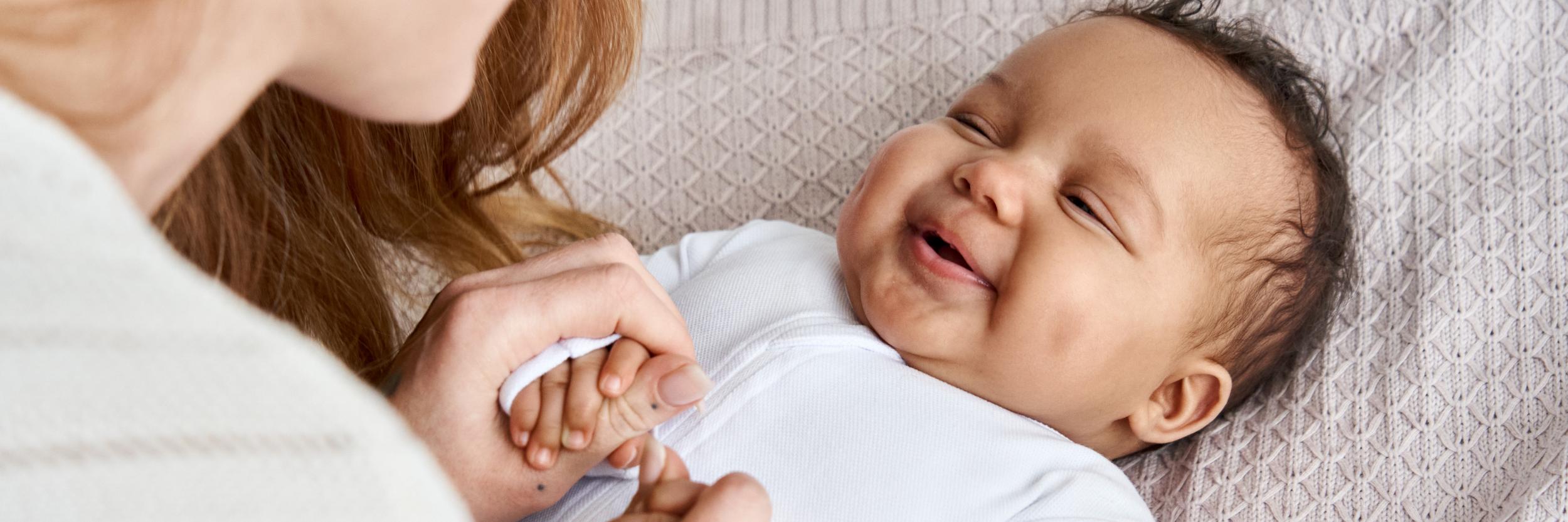 Eine Mutter schaut ihr Baby an, das Baby lacht.