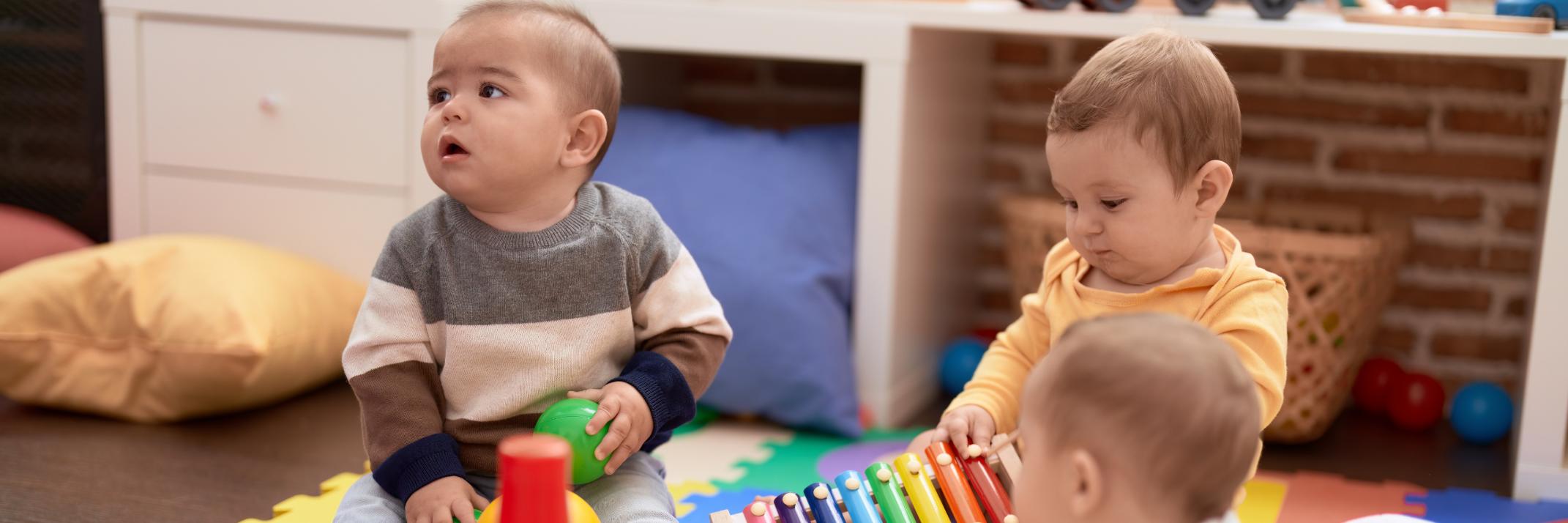 Drei Babys sitzen auf dem Boden und spielen mit Spielzeug