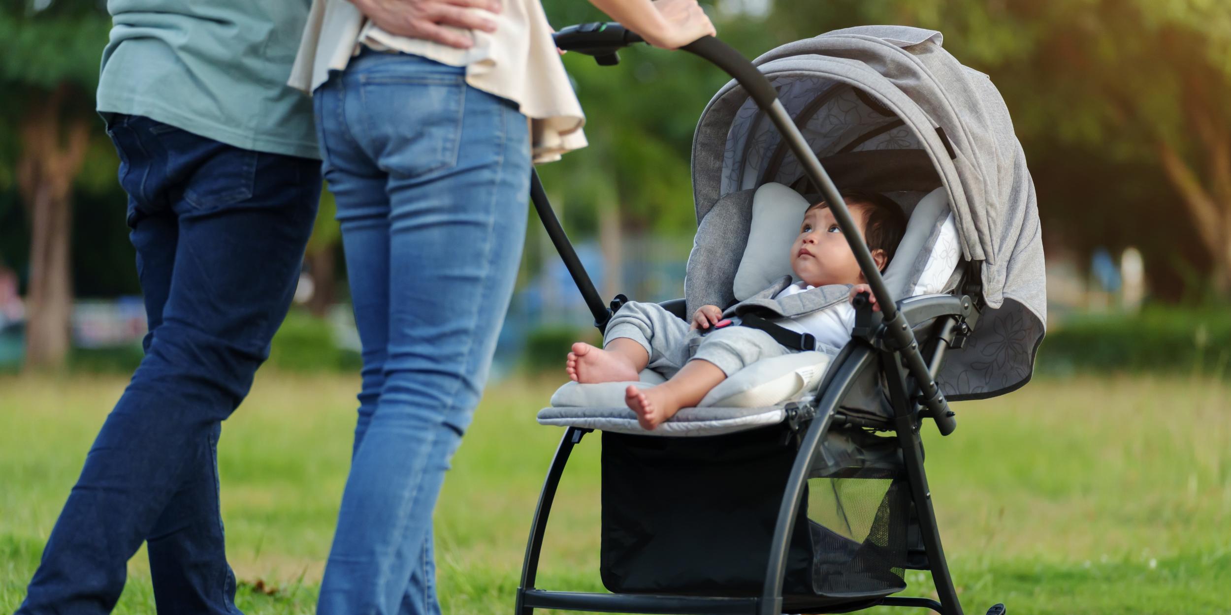 ein Paar schiebt Kleinkind, das im Kinderwagen sitzt