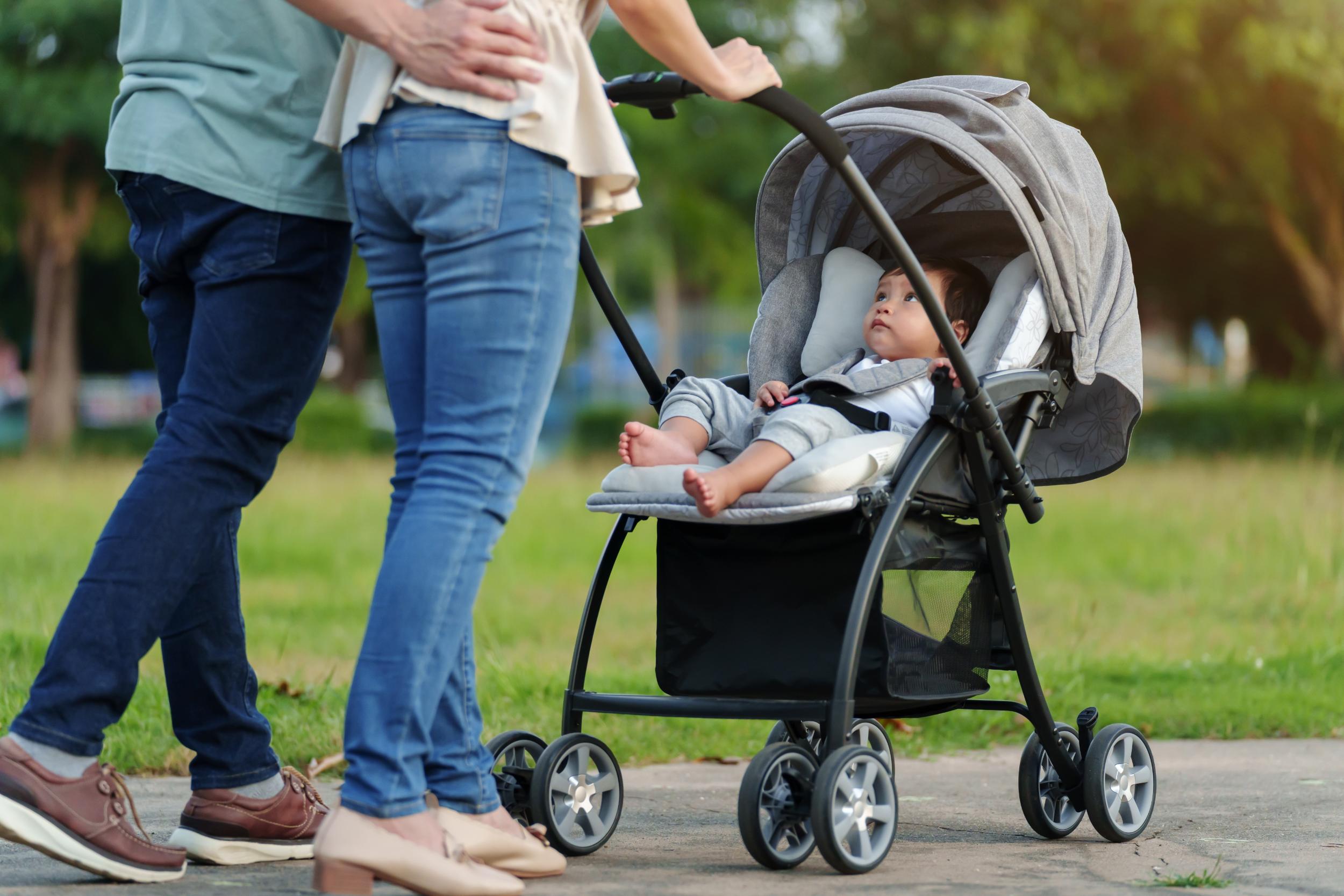 ein Paar schiebt Kleinkind, das im Kinderwagen sitzt
