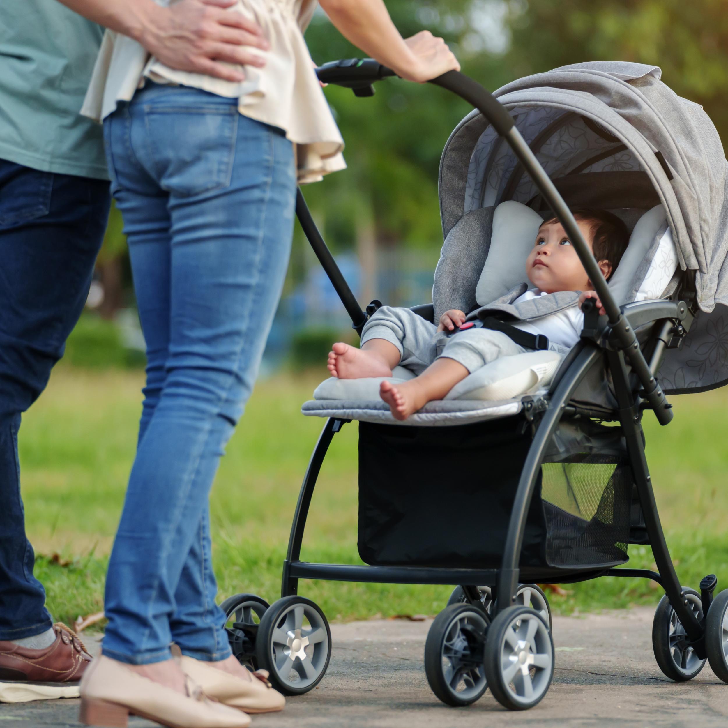 ein Paar schiebt Kleinkind, das im Kinderwagen sitzt