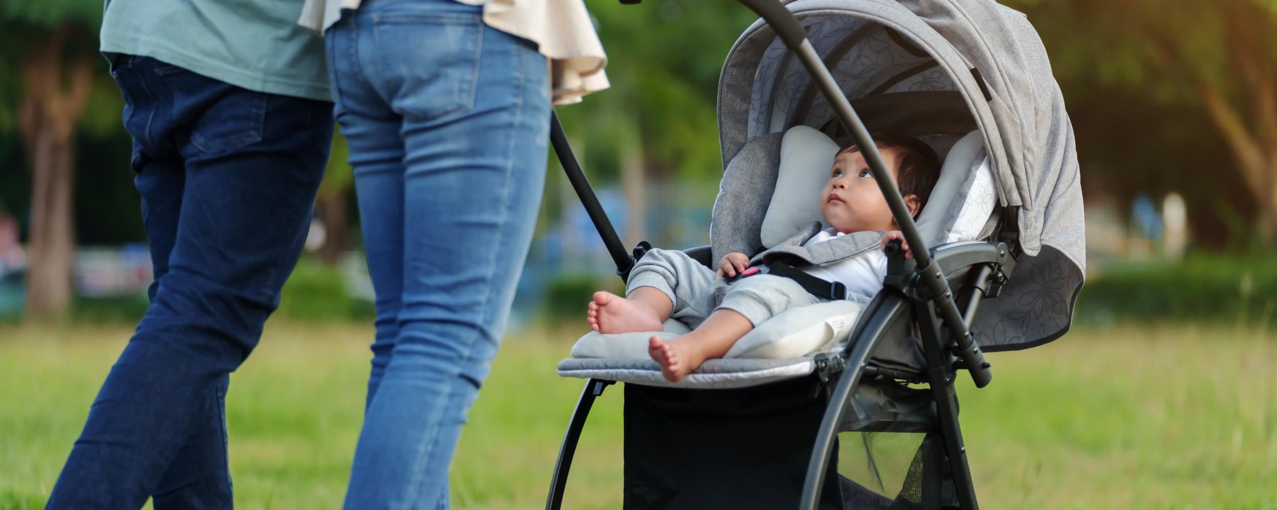 ein Paar schiebt Kleinkind, das im Kinderwagen sitzt
