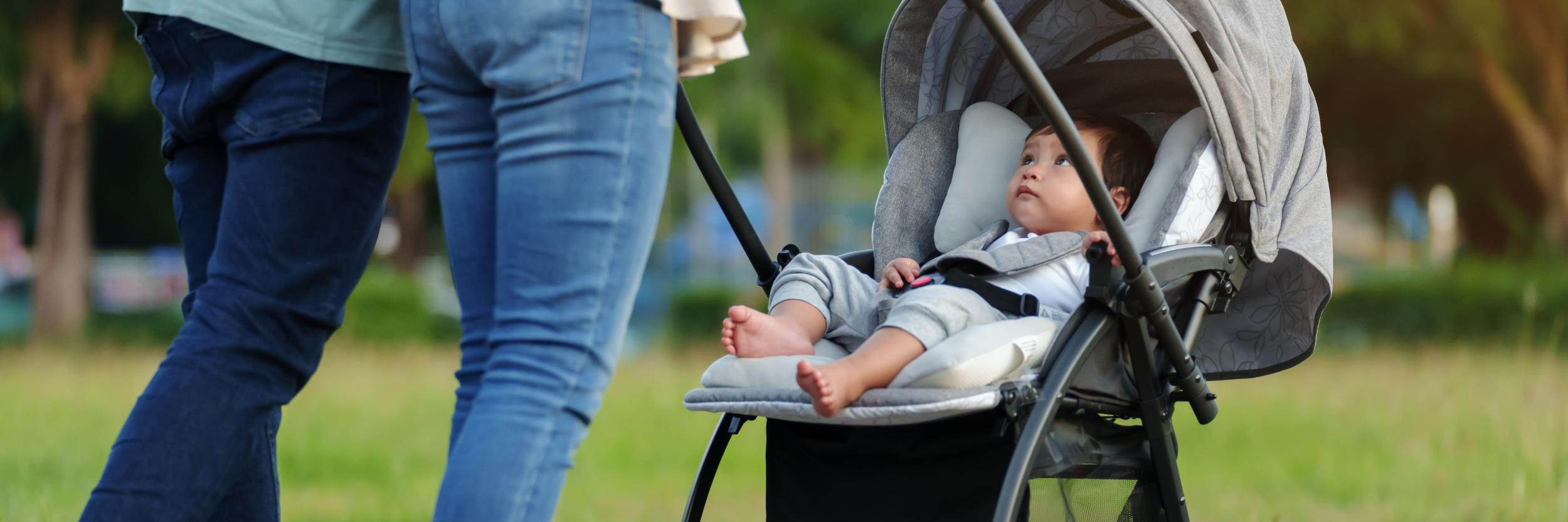 ein Paar schiebt Kleinkind, das im Kinderwagen sitzt