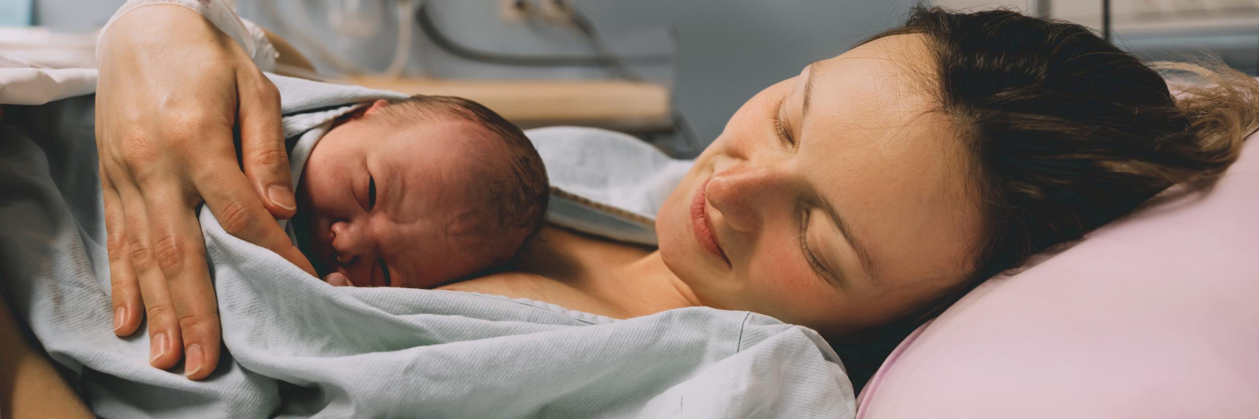 Mutter liegt im Bett mit neugeborenem Baby kurz nach der Geburt
