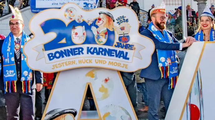Foto mit OB Dèus, dem Karnevalsmotto 2026 'Jestern, Hück und morje' und zwei Karnevalisten aus Bonn
