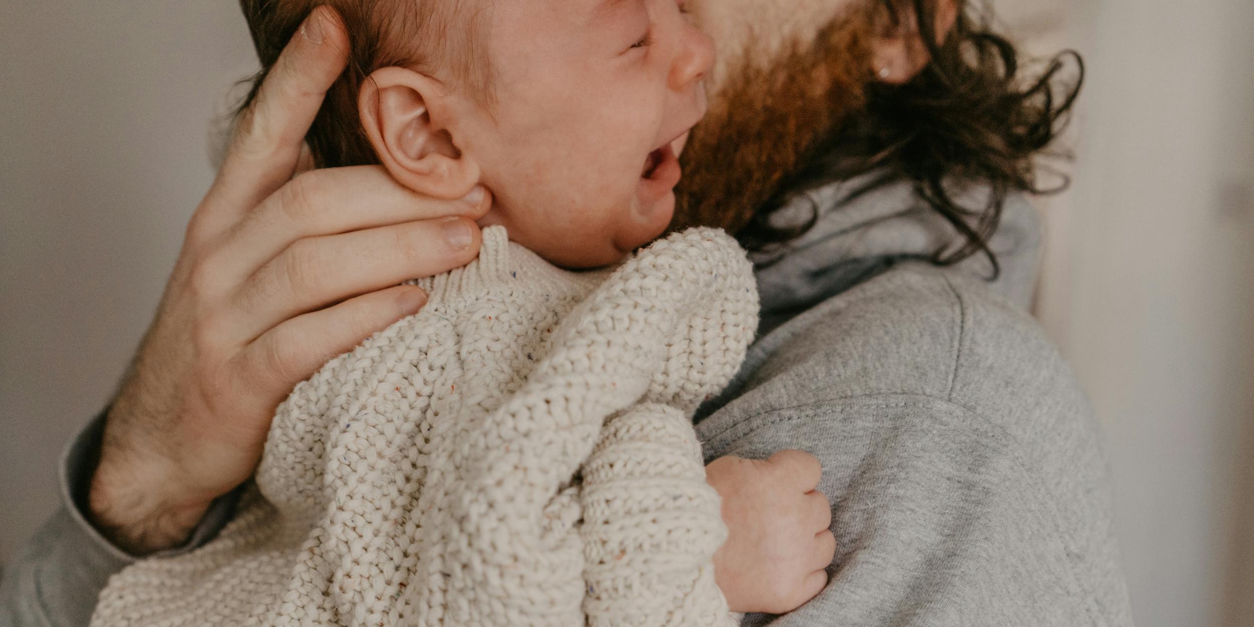 weinendes Baby auf dem Arm der Mutter