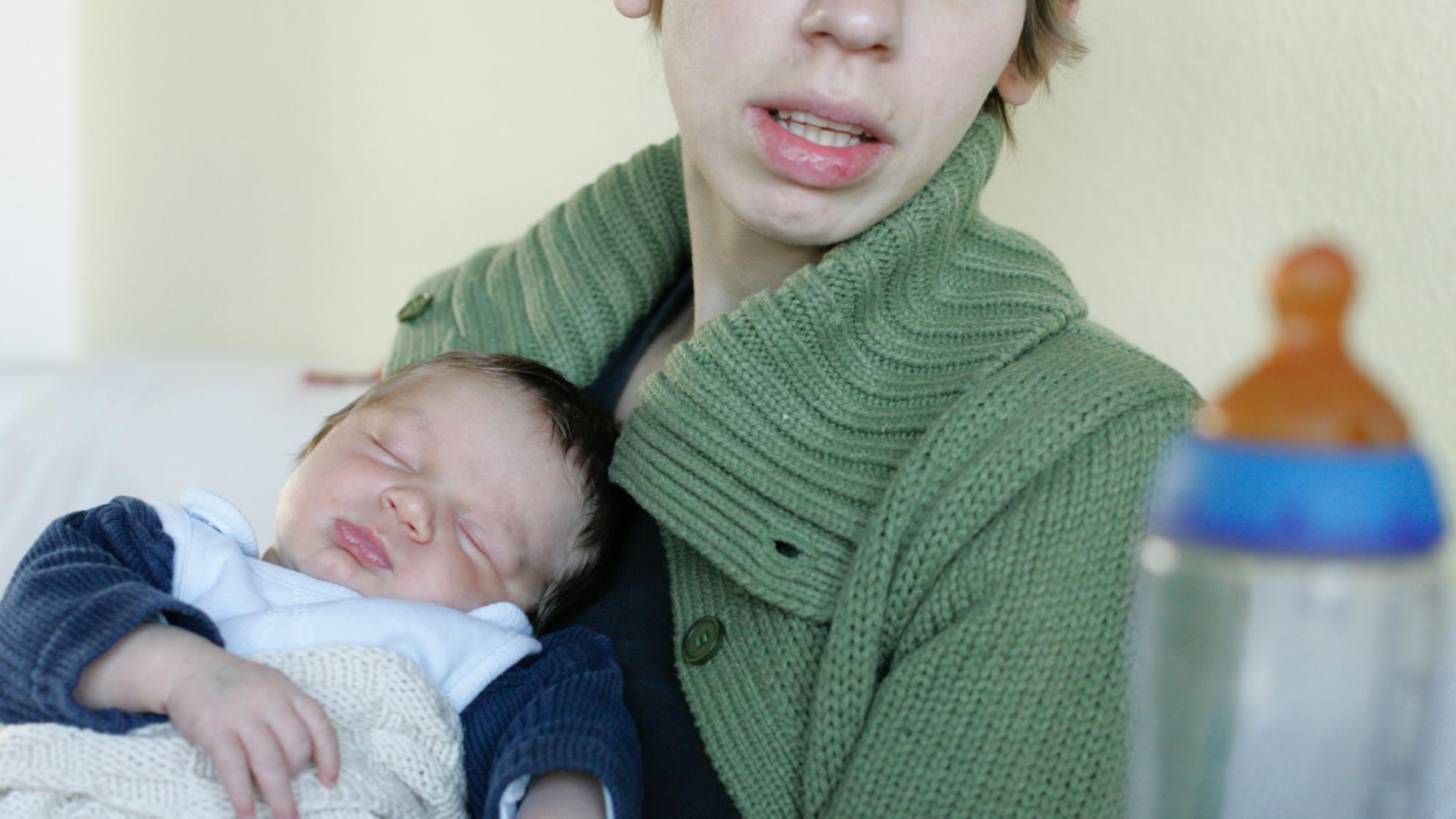 Mutter mit schlafendem Baby auf dem Arm, die überfordert aussieht